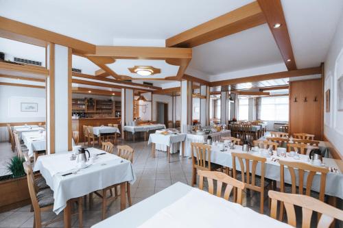 a restaurant with white tables and wooden chairs at Ferienwohnungen Karoly in Mörbisch am See