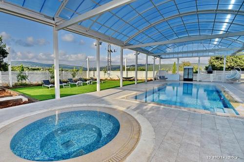 a large swimming pool with a clear glass ceiling at Lev Hahoresh Boutique Hotel in Shomera
