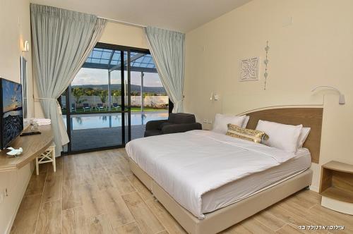a bedroom with a bed and a view of a pool at Lev Hahoresh Boutique Hotel in Shomera