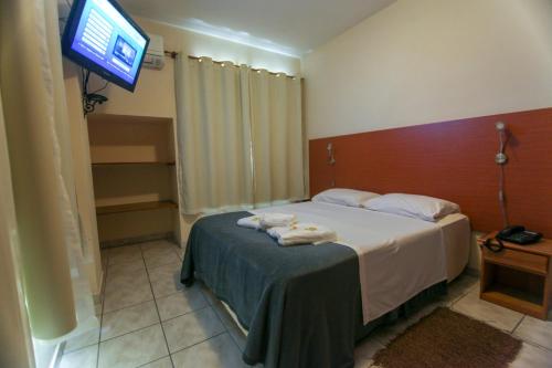 a hotel room with a bed with a television at Hotel Vila Rica Flat in Resende