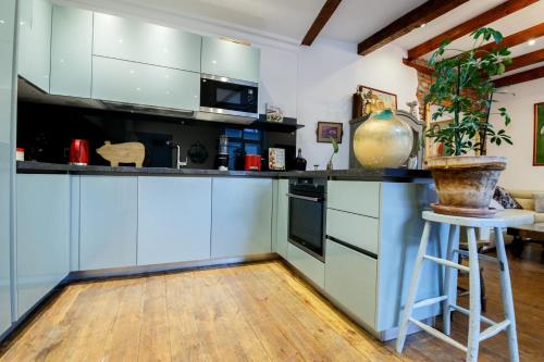 a kitchen with blue cabinets and a stool with a potted plant at Old Town Kalēju Street in Rīga