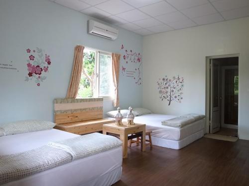 玉里鎮にあるJia Jia Homestayのベッド2台とテーブルと窓のある部屋