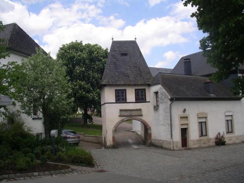 an old white house with an archway in a driveway at Apartment " Welwerwoltz " in Wilwerwiltz