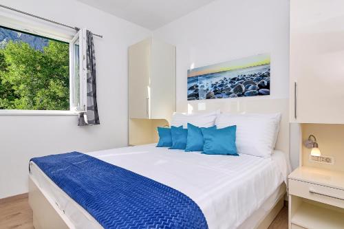 a white bedroom with a large bed with blue pillows at Holiday home Sergio in Bast