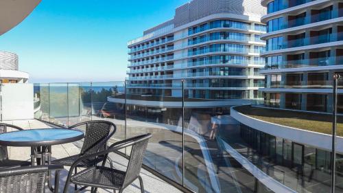 a balcony with chairs and a table and a building at Apartamenty Na Wyspie - Baltic Molo - Parking in Świnoujście