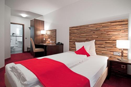 ein Schlafzimmer mit einem großen Bett mit einer roten Decke in der Unterkunft HIB Hotel in Baesweiler in Baesweiler