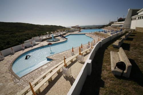a large swimming pool with benches in a resort at Sintra Sol - Apartamentos Turisticos in Sintra