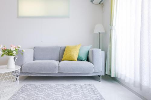 a living room with a gray couch with yellow pillows at Andnext Holiday House in Kyoto