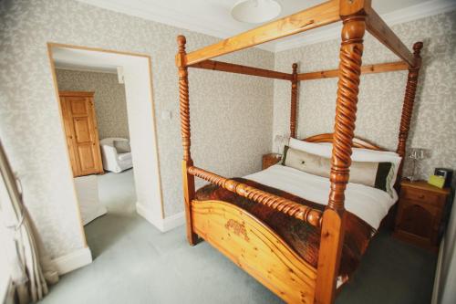 a bedroom with a wooden canopy bed in a room at Dufferin Coaching Inn in Killyleagh