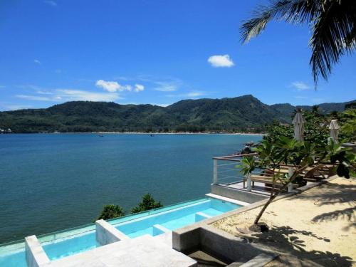 a swimming pool next to a body of water at Cape Sienna Phuket Gourmet Hotel & Villas - SHA Extra Plus in Kamala Beach