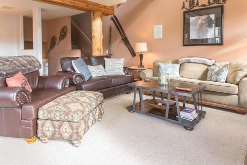 a living room with leather furniture and a table at Saddle Ridge Townhome | Unit J1 in Big Sky