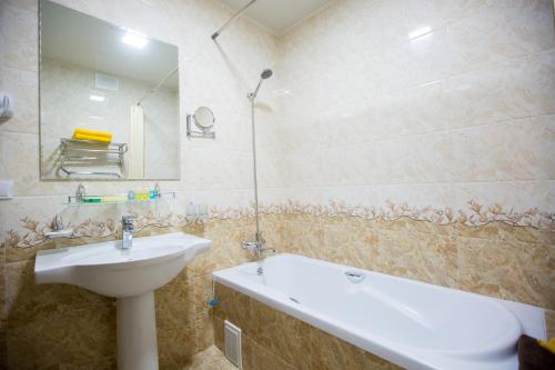 een badkamer met een wastafel, een spiegel en een bad bij Hotel Asia Khiva in Khiva