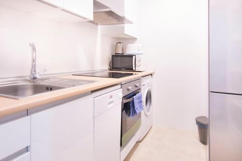 cocina blanca con fregadero y fogones en Cruz Apartment, en Madrid
