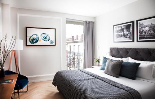a white bedroom with a bed and a window at Lasala Plaza Hotel - Adults Only in Donostia-San Sebastián