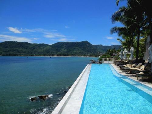 a swimming pool next to a body of water at Cape Sienna Phuket Gourmet Hotel & Villas - SHA Extra Plus in Kamala Beach