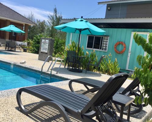 a couple of chairs and an umbrella next to a pool at Casa Tanjung Jara in Dungun
