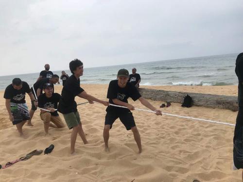 a group of men pulling a rope on the beach at Casa Tanjung Jara in Dungun