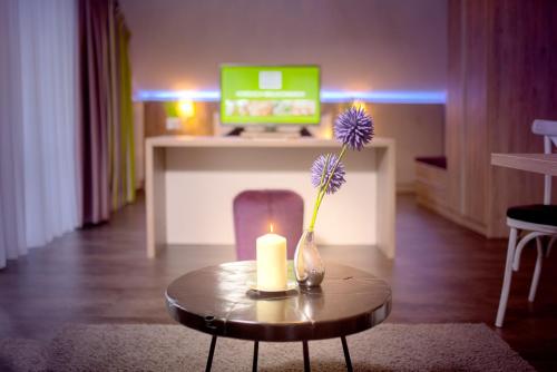 a candle and a vase with a flower on a table at Hotel-Restaurant Birkenhof in Bad Soden-Salmünster