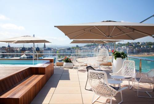 a patio with chairs and umbrellas on a roof at Lasala Plaza Hotel - Adults Only in Donostia-San Sebastián