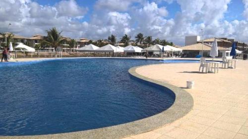 a swimming pool with chairs and umbrellas in a resort at Apartamento Condomínio Villa das Águas in Praia do Saco