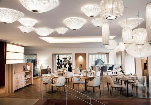a dining room with tables and chairs and chandeliers at Lasala Plaza Hotel - Adults Only in Donostia-San Sebastián