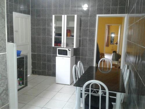 a kitchen with a white refrigerator and a table at Casa Praia Grande - Vila Caiçara in Solemar