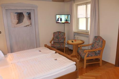 a bedroom with a bed and a table and chairs at DEVA Hotel-Restaurant Fischerwirt inklusive Chiemgau Card in Ruhpolding