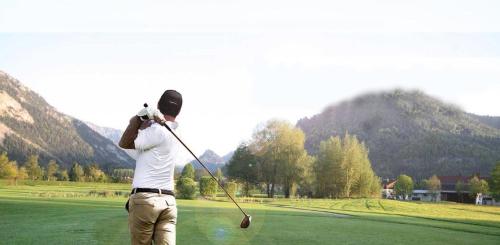 a man swinging a golf club on a golf course at DEVA Hotel-Restaurant Fischerwirt inklusive Chiemgau Card in Ruhpolding