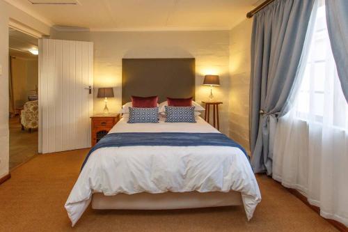 sypialnia z dużym łóżkiem z czerwonymi i niebieskimi poduszkami w obiekcie Hazenjacht Karoo Lifestyle - SPITZKOP w mieście Oudtshoorn