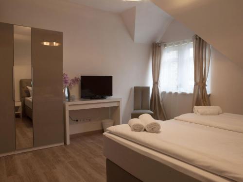 a bedroom with two beds and a desk and a television at Hotel Ravene in Cochem
