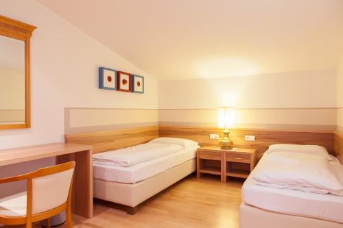 una camera con due letti e un tavolo con una lampada di Apartments Bachmair a Scena