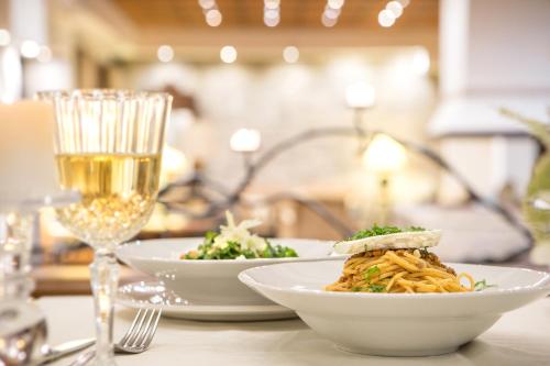 a table with two plates of food and a glass of wine at Country Club Hotel & Suites in Mikrón Khoríon