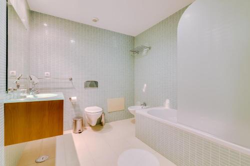 a bathroom with a tub and a toilet and a sink at Village Marina Olhão in Olhão