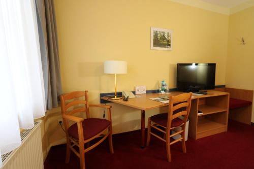 a hotel room with a desk with chairs and a television at Radduscher Hafen in Vetschau