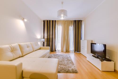 a living room with a white couch and a flat screen tv at Village Marina Olhão in Olhão