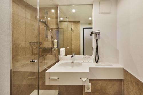 a bathroom with a sink and a shower at H+ Hotel Köln Brühl in Brühl