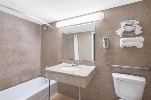 a bathroom with a sink and a toilet and a mirror at Days Inn by Wyndham Elmsford in Elmsford
