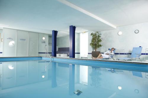 eine Frau auf einem Stuhl neben einem Pool in der Unterkunft Hotel Rennschuh in Göttingen