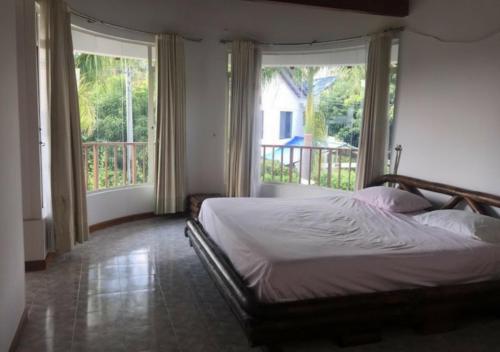 a bedroom with a bed and two large windows at Casa Quinta con piscina privada Girardot in Girardot