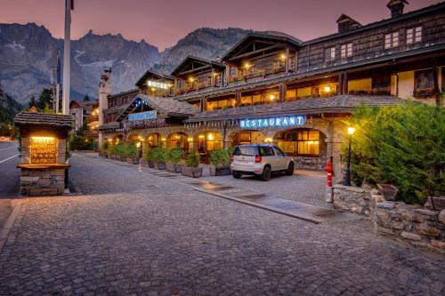 een auto geparkeerd voor een gebouw met bergen bij iH Hotels Courmayeur Mont Blanc in Courmayeur