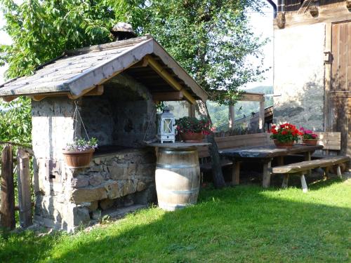 a stone barbecue with a table and a bench at Schartnerhof in Collalbo