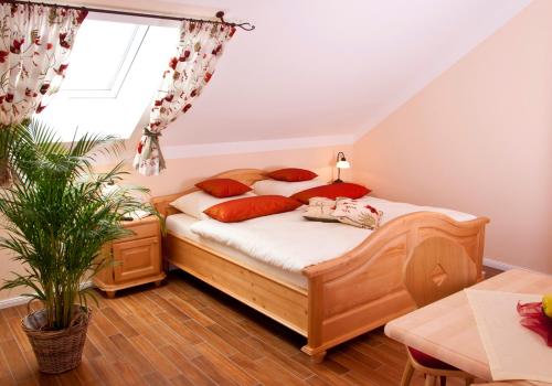 a bedroom with a bed with red pillows and a window at Pension Weindl in Notzing