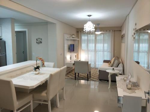 ein Esszimmer und ein Wohnzimmer mit einem Tisch und Stühlen in der Unterkunft Don Rafael 02 dormitórios, 80m mar, Mariscal in Bombinhas