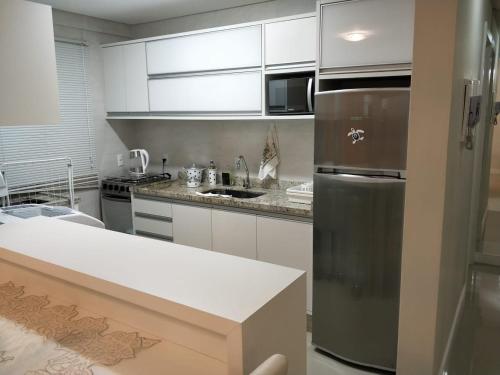 cocina con armarios blancos y nevera de acero inoxidable en Don Rafael 02 dormitórios, 80m mar, Mariscal, en Bombinhas
