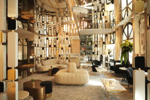 a lobby with chandeliers and tables and chairs at Hôtel le Derby Alma by Inwood Hotels in Paris
