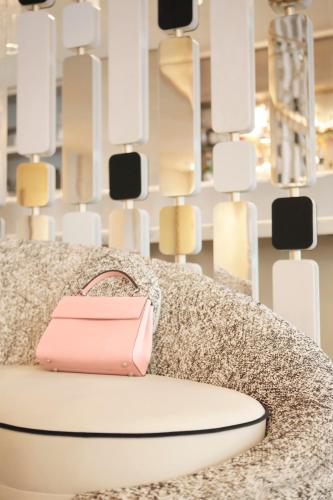 a pink bag sitting on a couch in front of a display at Hôtel le Derby Alma by Inwood Hotels in Paris