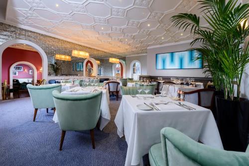 コークにあるThe Metropole Hotel Corkの白いテーブルと椅子のあるダイニングルーム