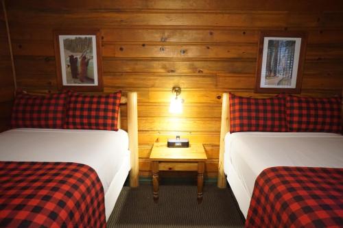 a room with two beds and a table between them at Shaver Lake Village Hotel in Shaver Lake