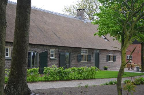 a brick house with a green door and trees at Erfgoed & Logies Den Heijkant in Moergestel