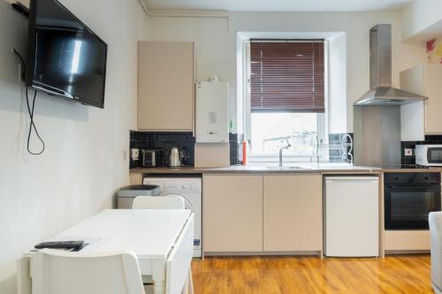 uma cozinha com armários brancos e uma mesa e cadeiras brancas em Fraser Apartment em Aberdeen
